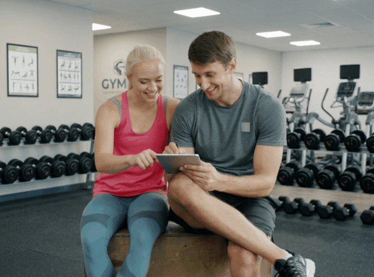 Registered dietitian and certified personal trainer providing online telehealth fitness and nutrition consultation to a client in a gym