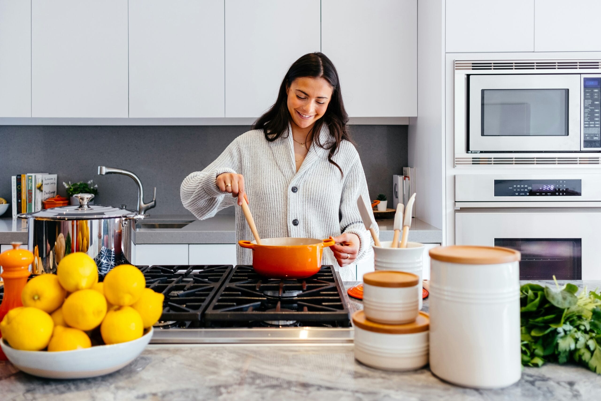 A woman is stirring a pot in a modern kitchen.